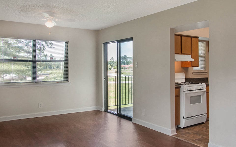 an empty living room and kitchen with a door to a balcony