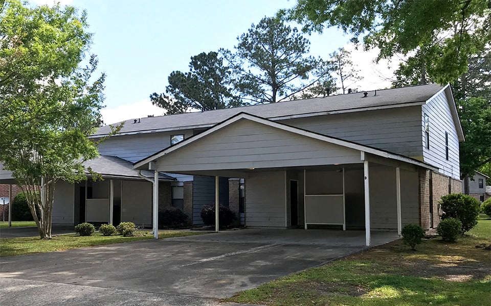 a white house with a driveway and trees