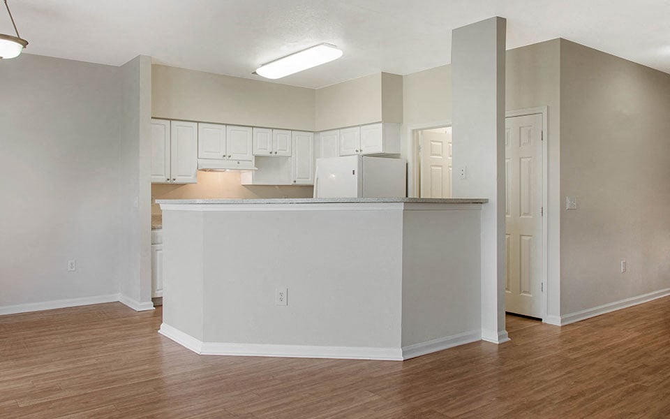 an empty living room and kitchen with a counter top