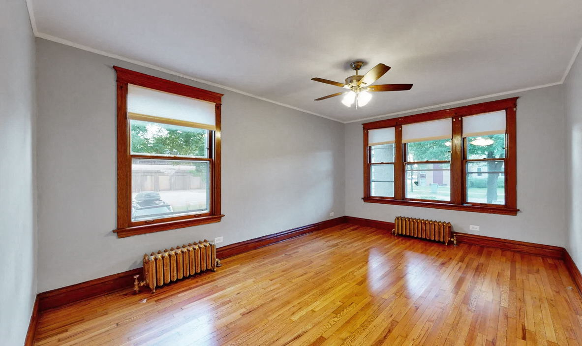 an empty living room with wood floors and a ceiling fan