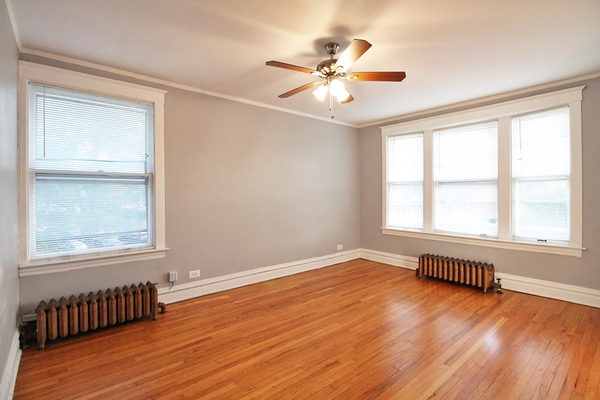 an empty living room with a ceiling fan and wood floors