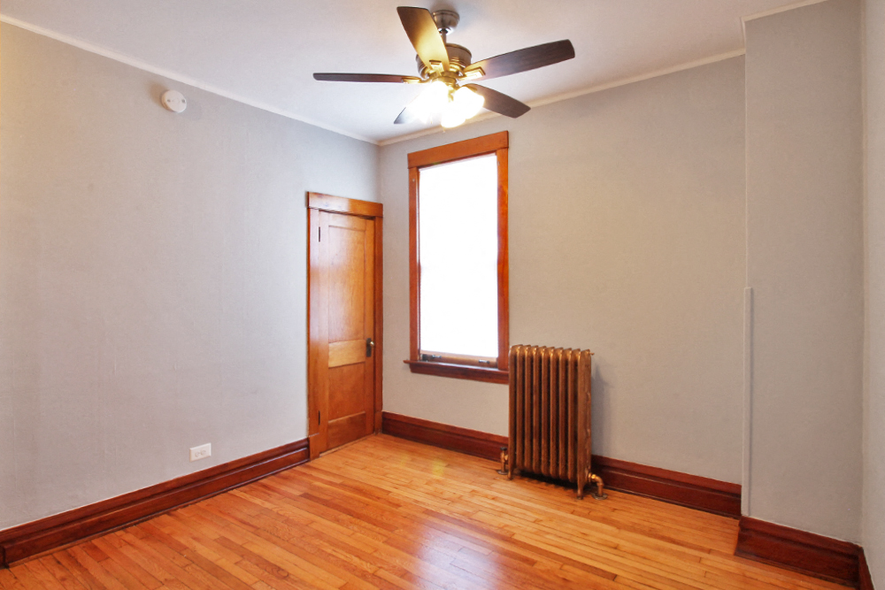 an empty room with a radiator and a ceiling fan