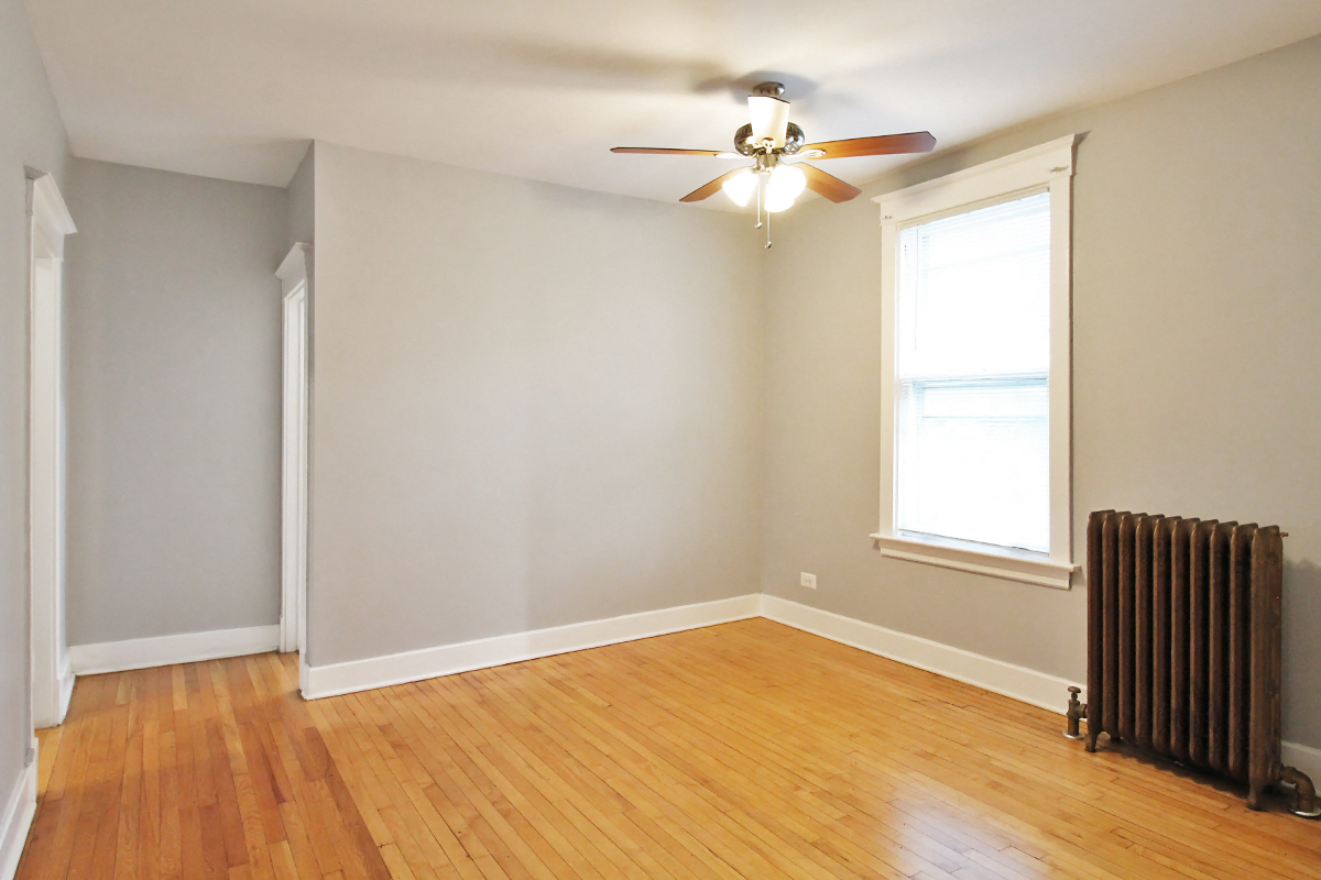 an empty room with a radiator and a ceiling fan