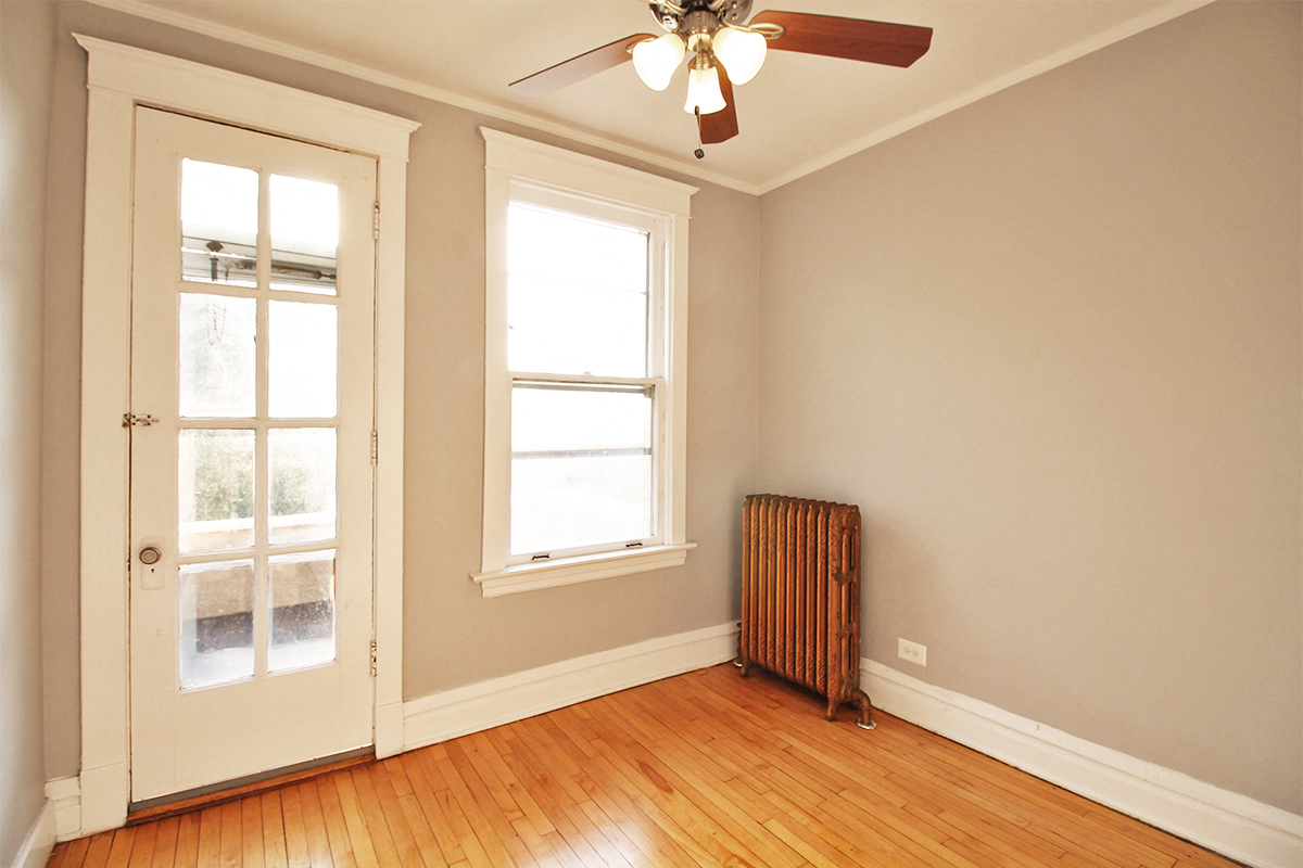 an empty room with a ceiling fan and two windows