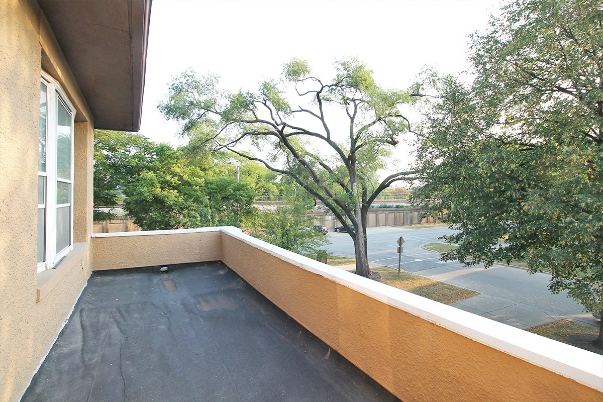 a balcony with a view of trees and a parking lot