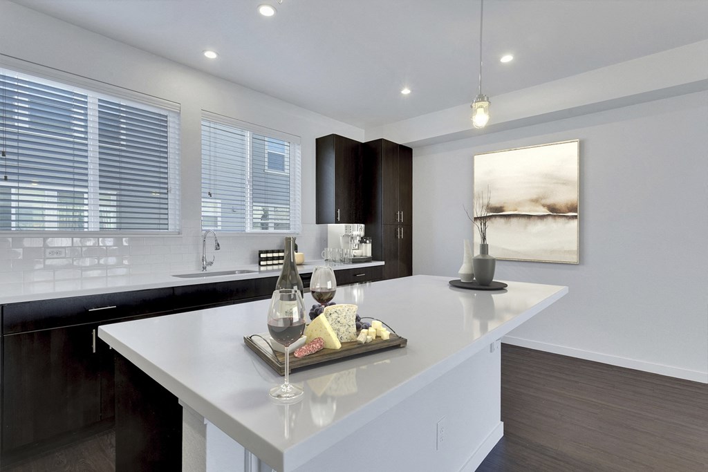 a kitchen with a large island with a bottle of wine and wine glasses on it