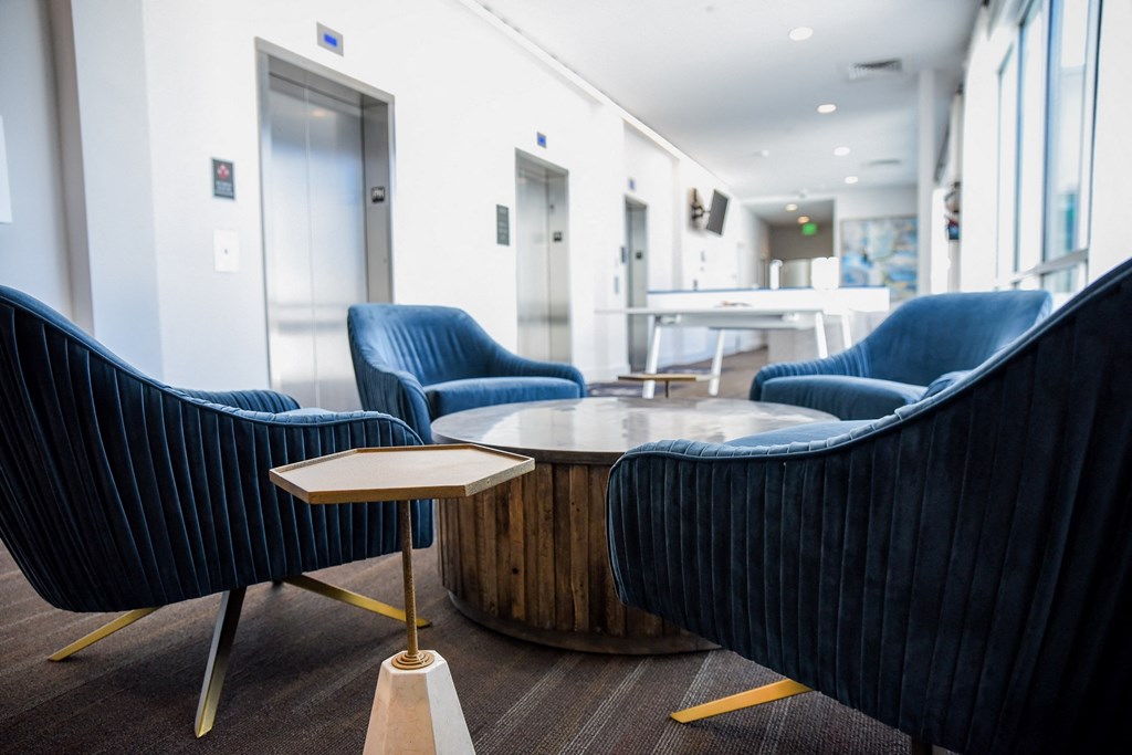 a lounge area with blue chairs and a coffee table