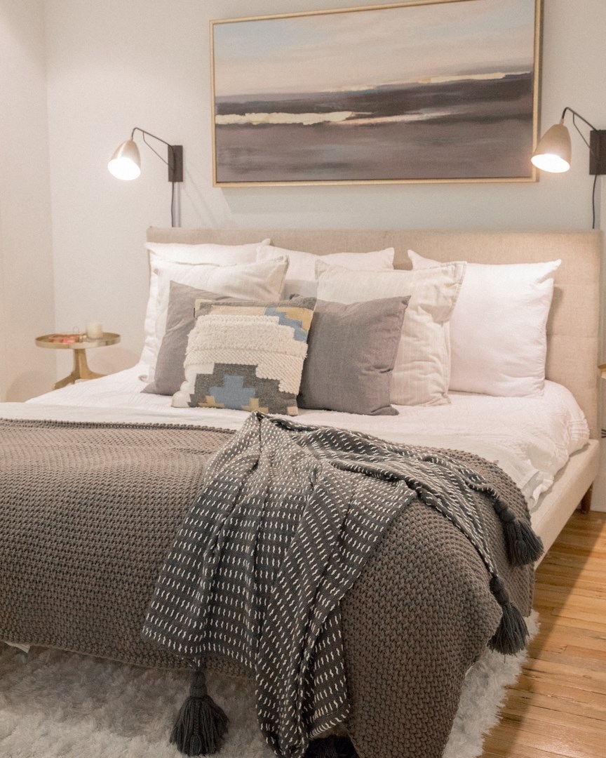 a bedroom with a bed and pillows and a painting on the wall