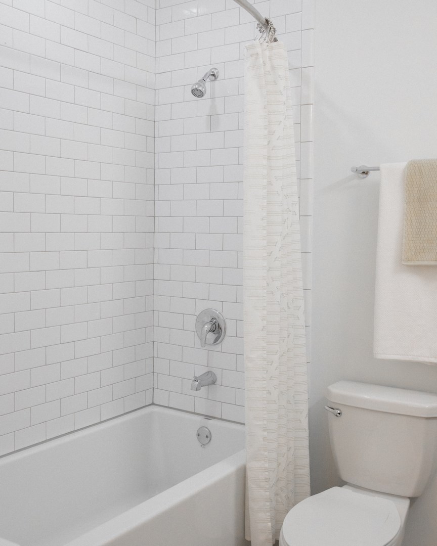 a white bathroom with a shower and a toilet