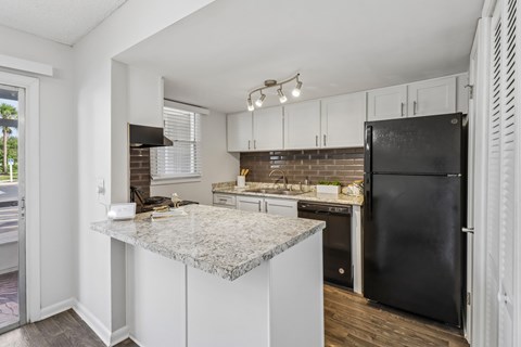 A kitchen with a granite countertop and black appliances.