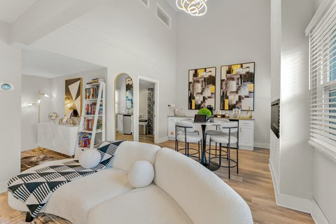 A white couch with a black and white patterned pillow sits in a bright living room.