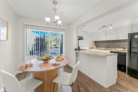 A kitchen with a table and chairs in front of a window.