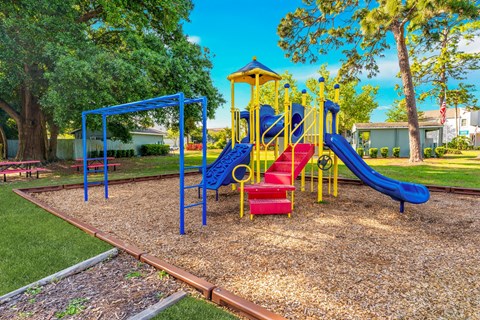 A playground with a blue slide and red chairs.