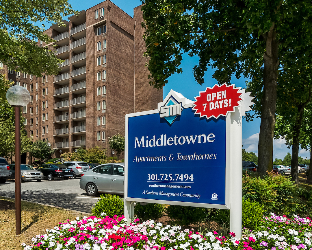 a sign in front of an apartment building with flowers