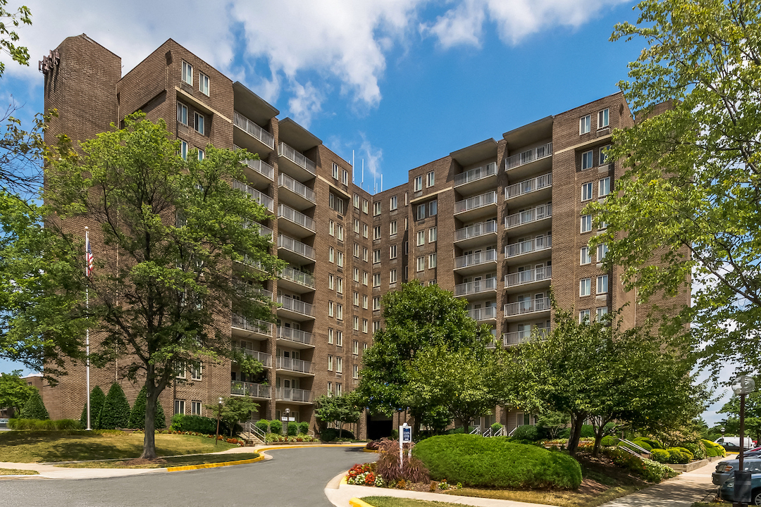a large apartment building with trees and a street in front
