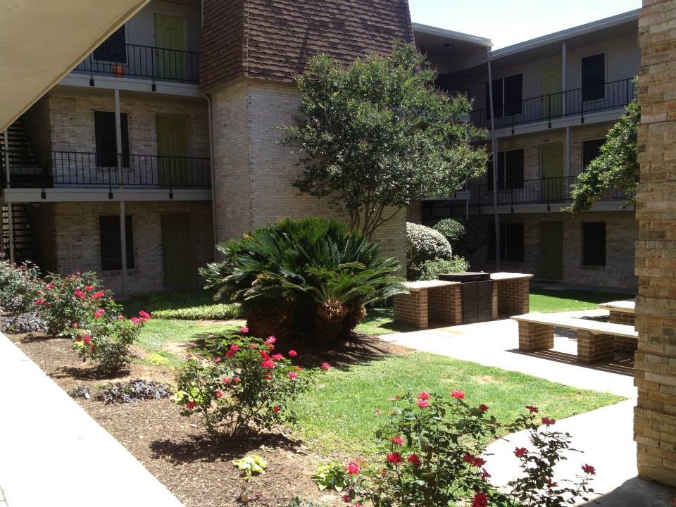the courtyard of an apartment building with plants and flowers