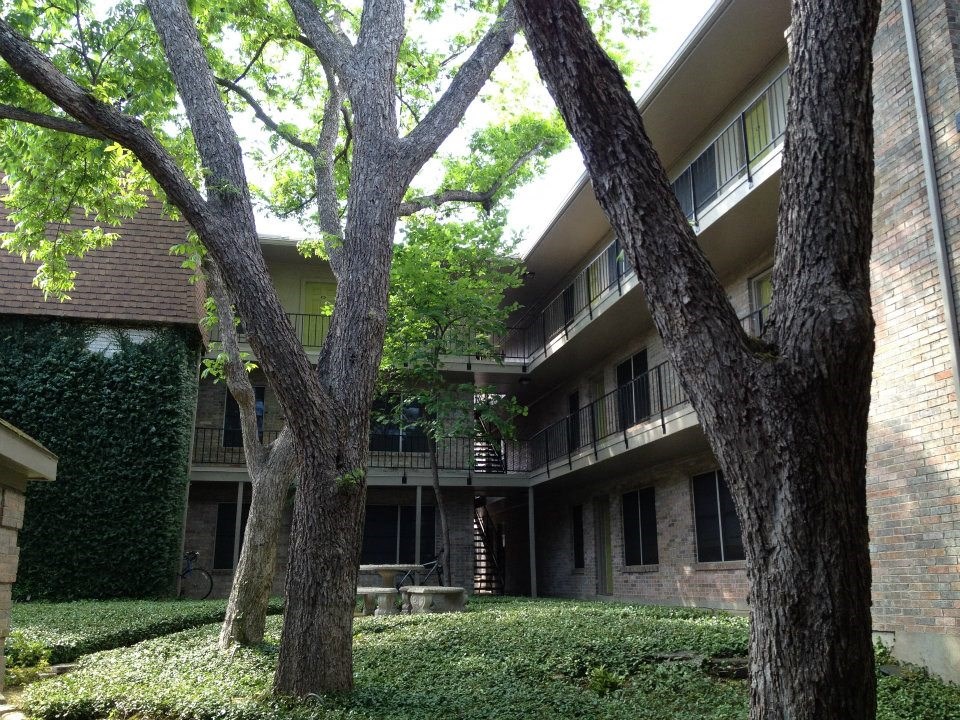 the courtyard of an apartment building with trees