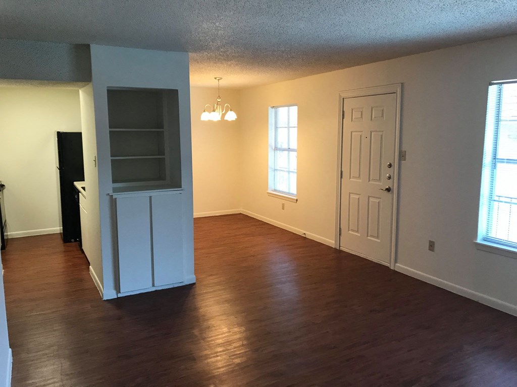 an empty living room with a hard wood floor and a white door