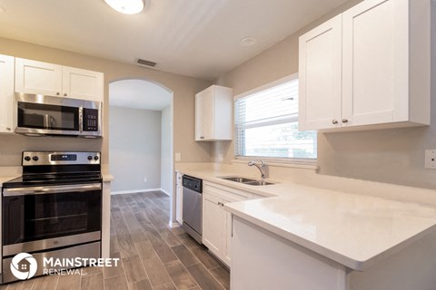 a kitchen with white cabinets and stainless steel appliances and a window