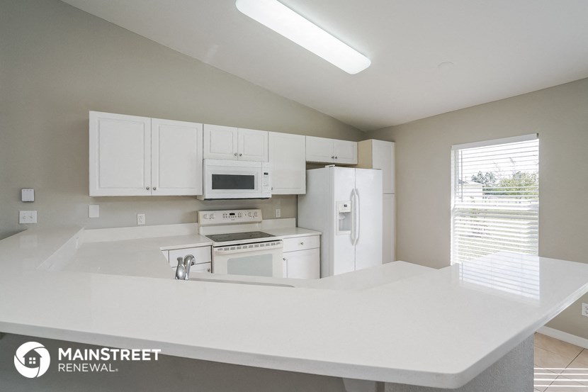 a kitchen with white cabinets and appliances and a white counter top