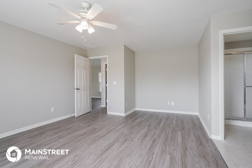 the living room of an apartment with wood flooring and a ceiling fan
