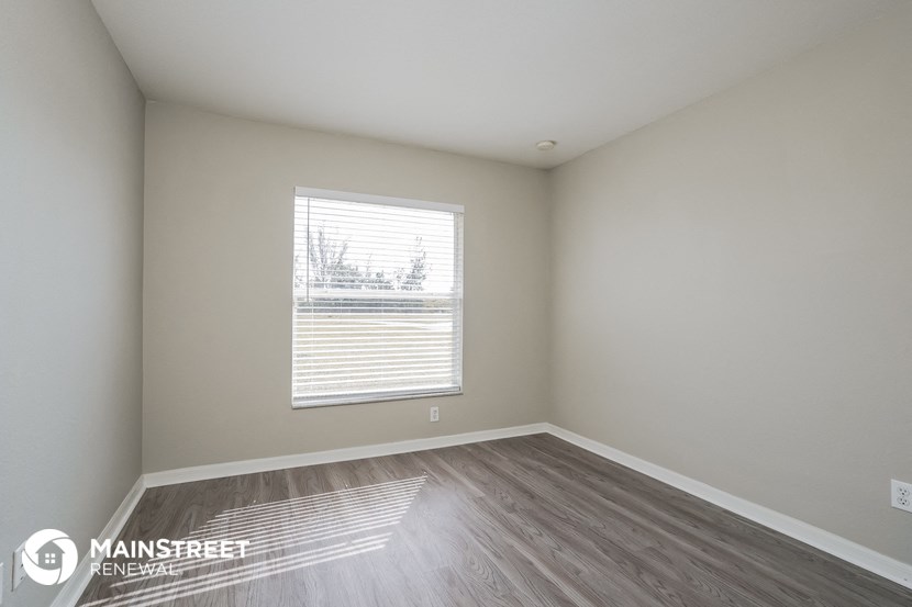 the interior of an empty room with wood flooring and a window