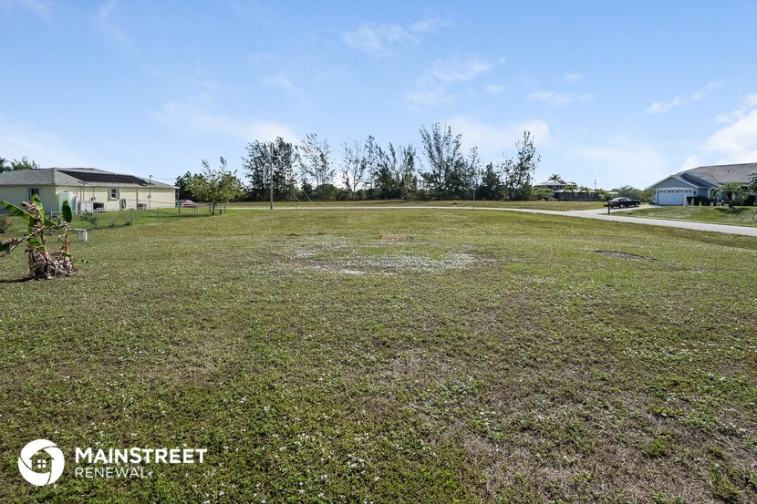 a large yard with a house in the background and a road