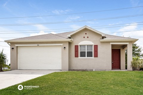 a beige house with red shutters and a lawn