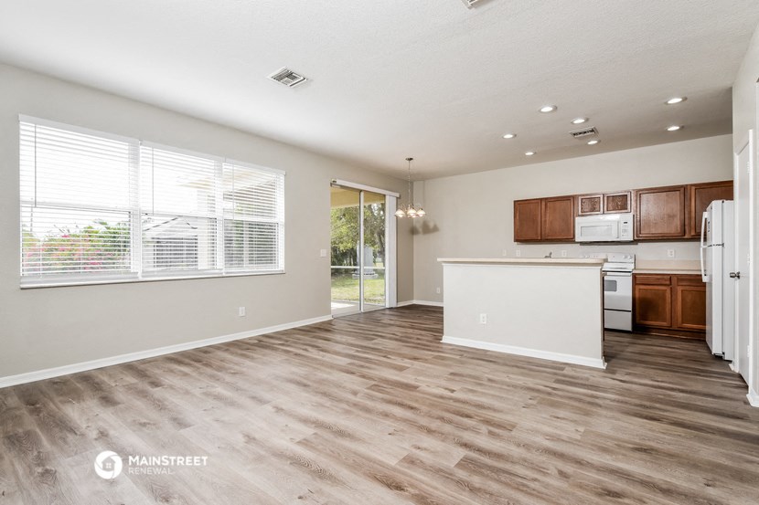 the living room and kitchen of a house with wood flooring