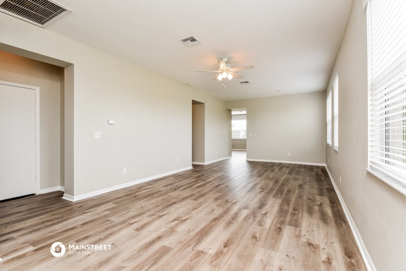the living room and dining room with wood flooring and a ceiling fan