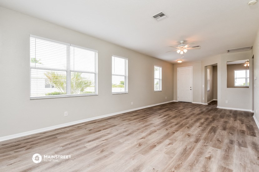 the living room of a new home with wood flooring and a ceiling fan