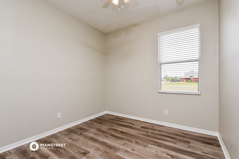 the spacious living room with wood flooring and a window