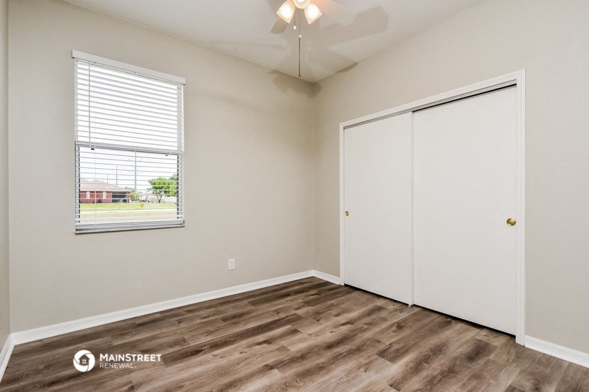 the spacious living room with a window and a door to the bedroom
