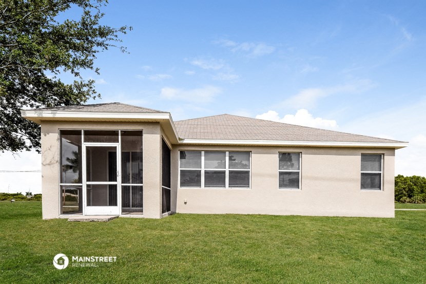 a small tan house with a lawn and a tree
