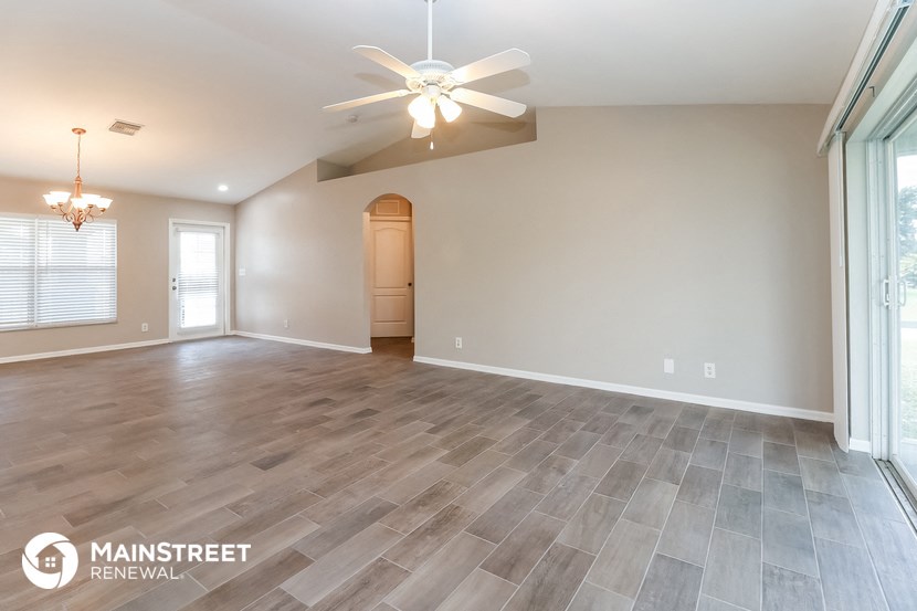 the living room and dining room with wood flooring and a ceiling fan