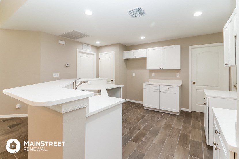 a kitchen with white counter tops and white cabinets and tile floors