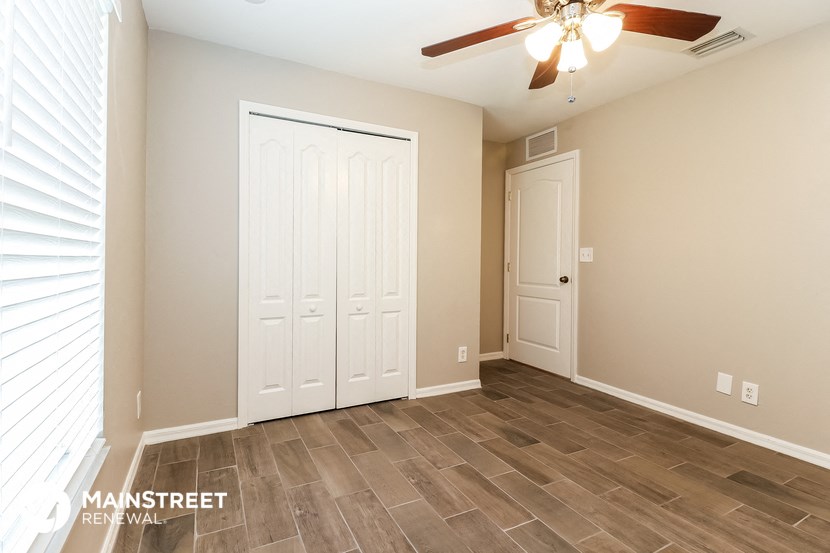 the living room with two closets and a ceiling fan