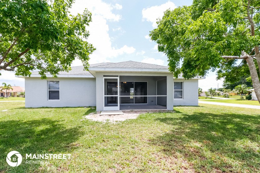 a small white house with a yard and trees