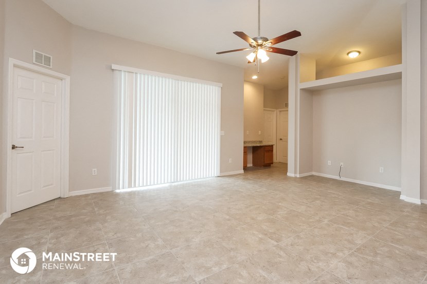 an empty living room with a ceiling fan