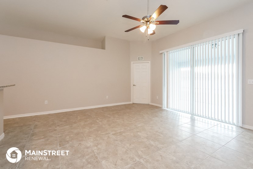 an empty living room with a ceiling fan and a large window
