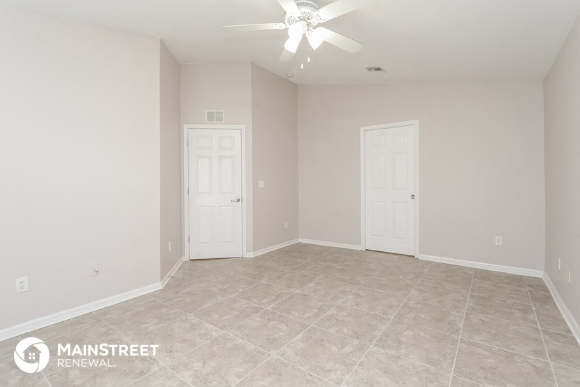 the spacious living room with tile flooring and a ceiling fan