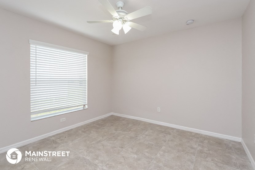 the upstairs bedroom with a large window and a ceiling fan