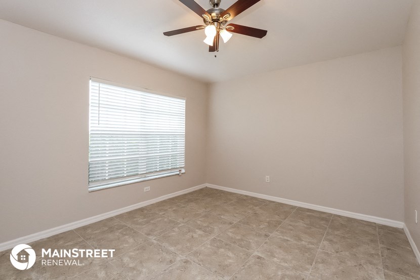 the spacious living room with tile flooring and a ceiling fan