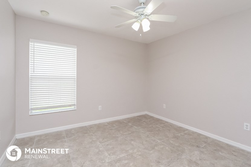the upstairs bedroom has a large window and a ceiling fan