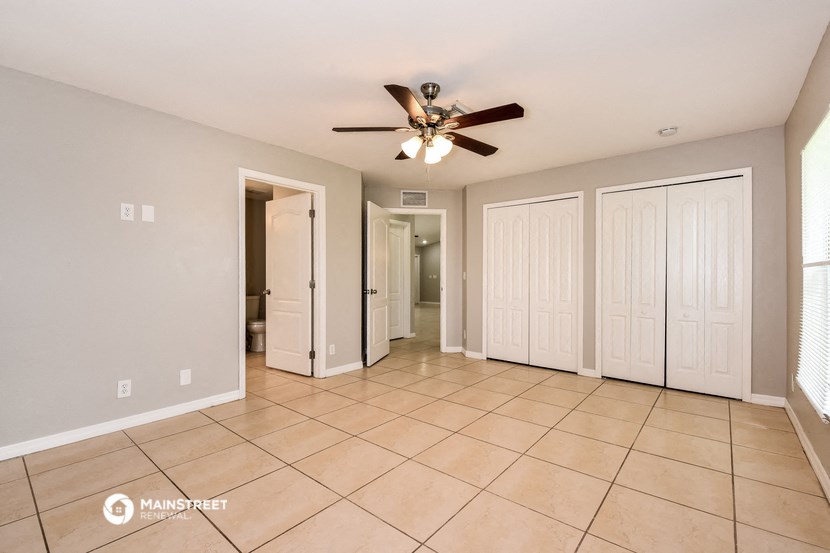 the living room has tile flooring and a ceiling fan