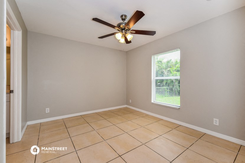 an empty living room with a ceiling fan and tiled floors