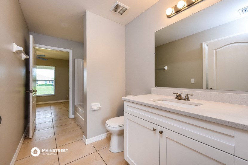 a bathroom with a large mirror and a sink and a toilet