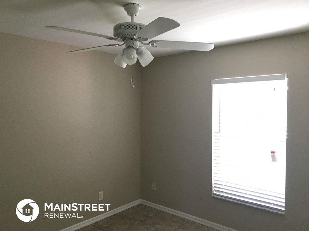 a ceiling fan in the corner of a room with a window