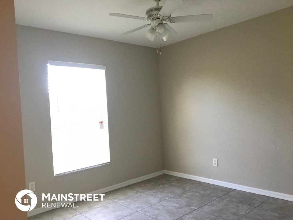 an empty room with a ceiling fan and a window