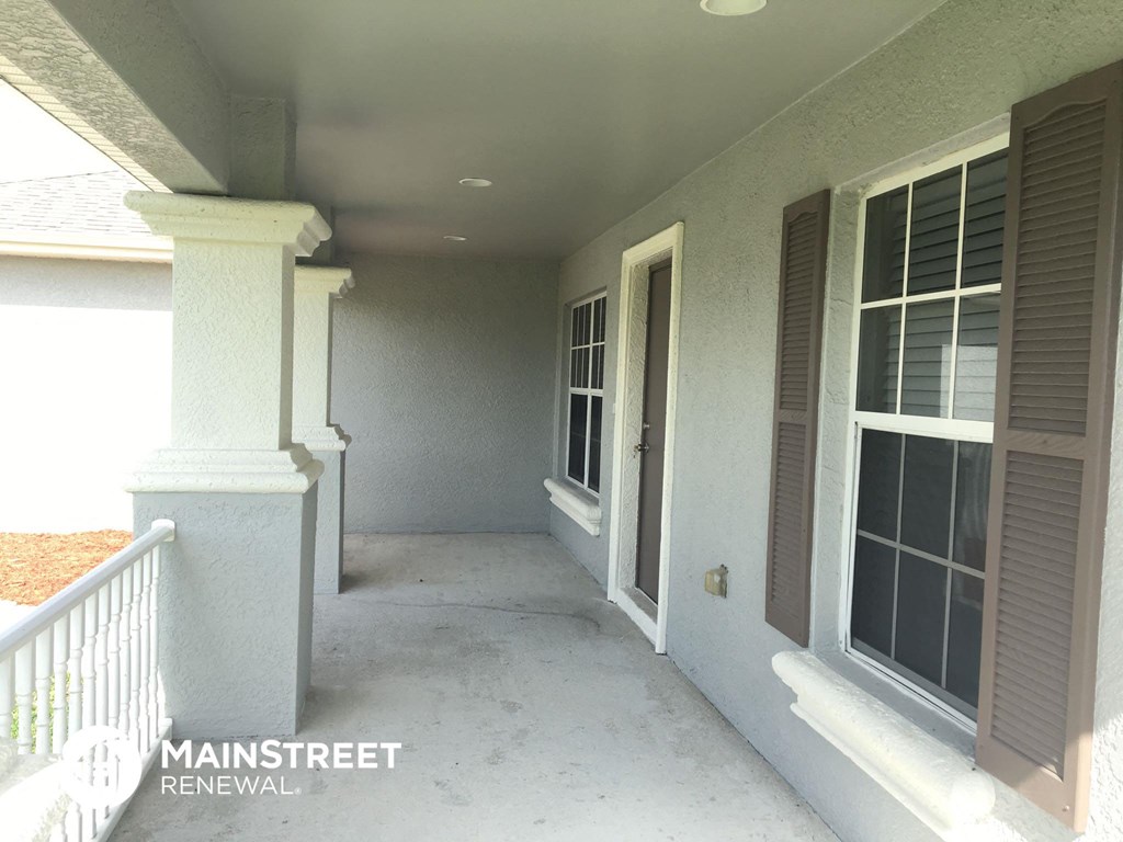 a covered porch with white columns and windows